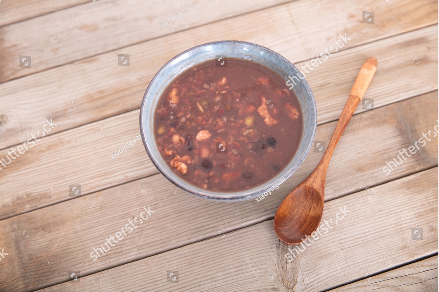 A steaming bowl of Laba porridge topped with dried fruits, nuts, and red dates in a traditional ceramic bowl