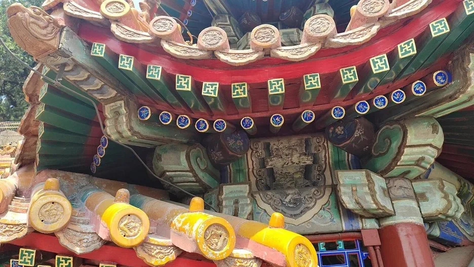 Golden glazed roof tiles of the Forbidden City gleaming against a blue sky, dragon finials at the ridge
