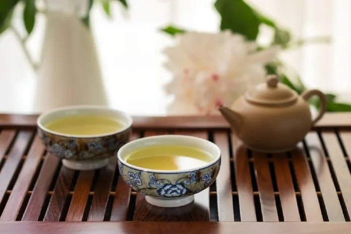 Tea being poured from a small clay pot into delicate cups during a gongfu tea session