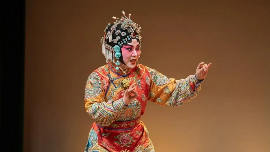 A Pingju performer in plain, elegant costume mid-gesture, the soft naturalism of the people's opera evident in her relaxed, expressive stance